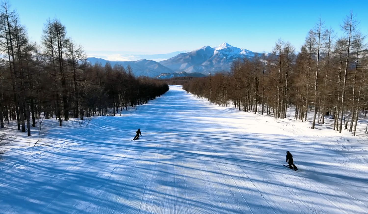 A couple of skiers on a long groomed run at Grandeco