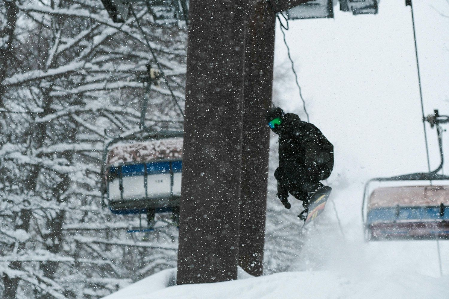 Snowboarder under the lift line hitting a kicker